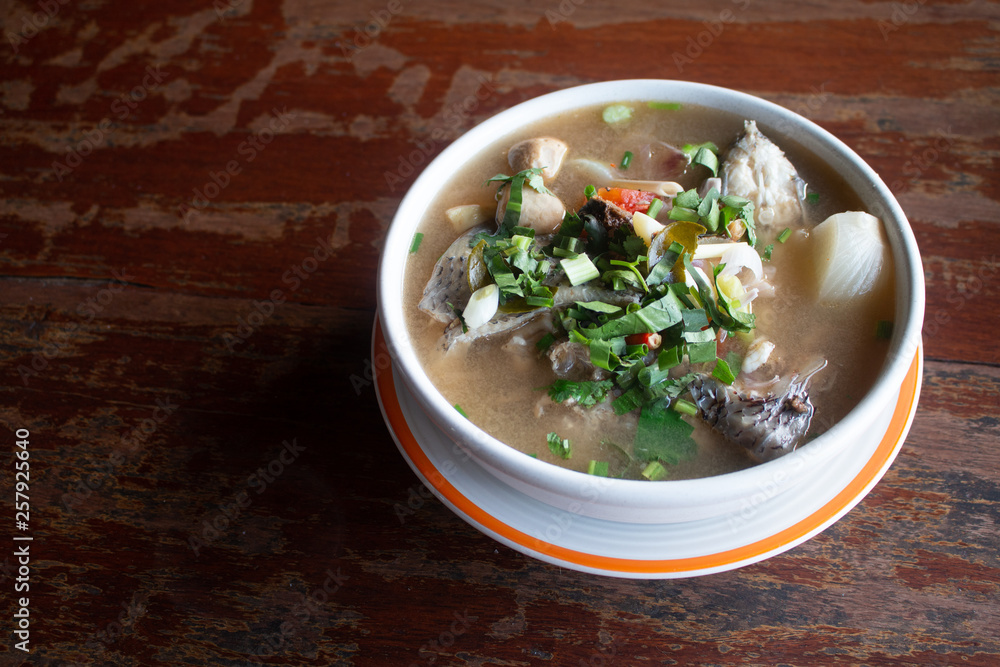 Spicy fish soup flavored with lemongrass and lime served on wooden table Spicy fish soup flavored with lemongrass and lime served on wooden table