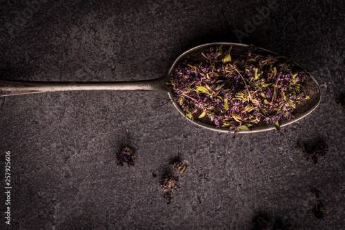 Dry Tea Leafs in Rustic Spoon on Dark Stone Background