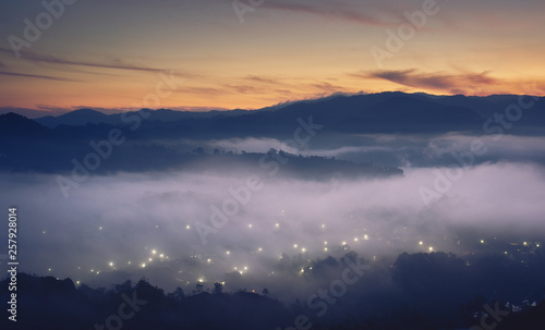 Morning fog over City lights, Aerial view of tropical rain forest in the mist, Landscape morning fog on Baan Hatsompaen Viewpoint Ranong Tropical rain forest at southern of Thailand