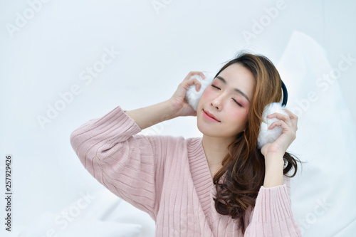 Winter Concept. Beautiful woman is relaxing in bedroom. Woman wearing a sweater in white bedroom.