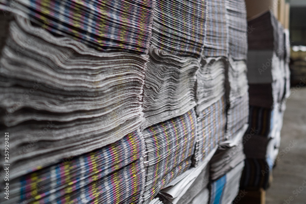 A large number of the issued newspapers in the printing house shop. A heap of multi-colored newspapers lie the friend on the friend A large number of the issued newspapers in the printing house shop. A heap of multi-colored newspapers lie the friend on the friend