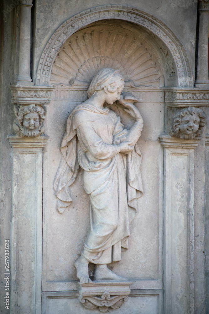 Relief Statue aus Stein einer jungen Frau mit einem Vogel in der Hand und zwei Putten auf dem Dorotheenstädtischen Friedhof in Berlin
