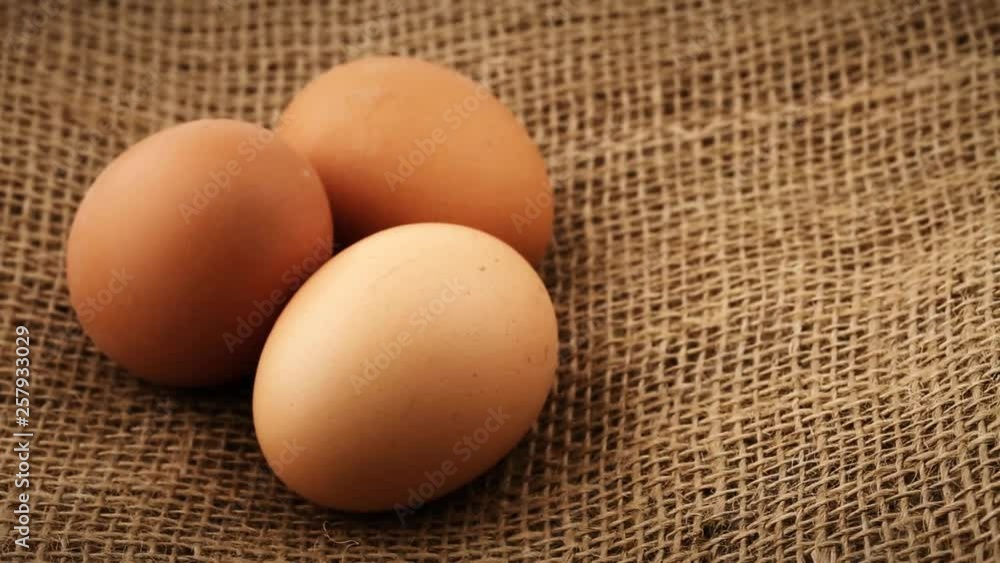 Three fresh brown chicken eggs rotating on burlap fabric background Three fresh brown chicken eggs rotating on burlap fabric background