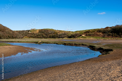 View of Parkmill Pill leading to Three Cliffs Bay on the Gower Peninsular at low tide. The river runs into the sea in the bay