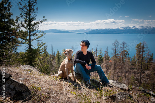 Woman with weimaraner dog sitting on rock 