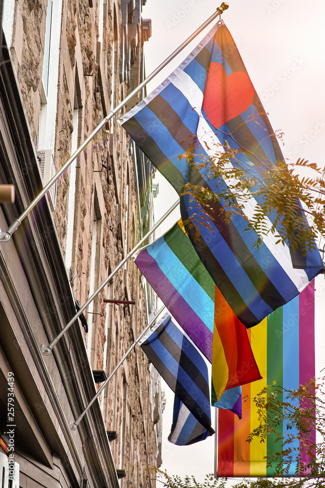 LGBT rainbow flag waving on the flag pole of a brick building in sainte catherine street, montreal, canada