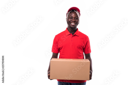 Portrait of Happy African American delivery man in red cloth walking to send a box package to customer isolated on white background © F8  \ Suport Ukraine