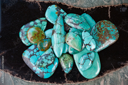 Pile of polished turquoise stones on black surface photo