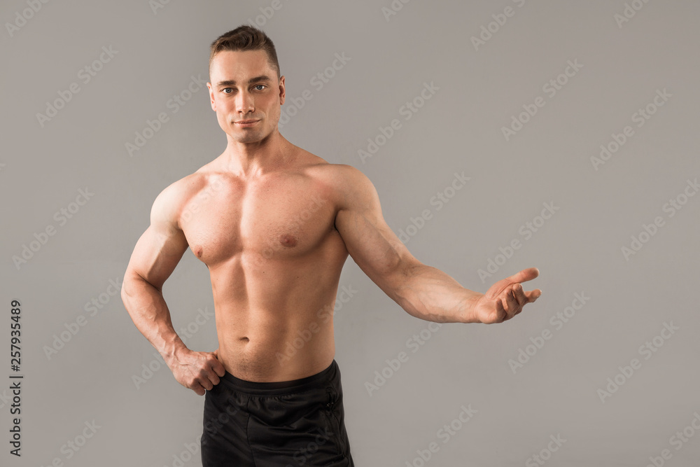 handsome man with muscles on gray background with muscles with hand gesture