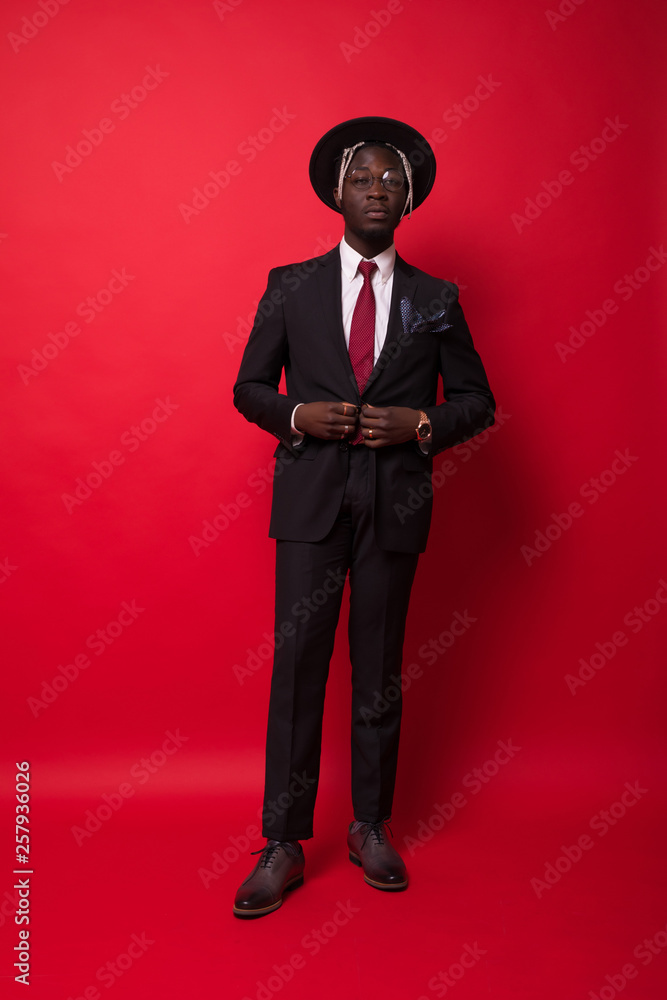 African-American Businessman dressed in suit and hat isolated on red background