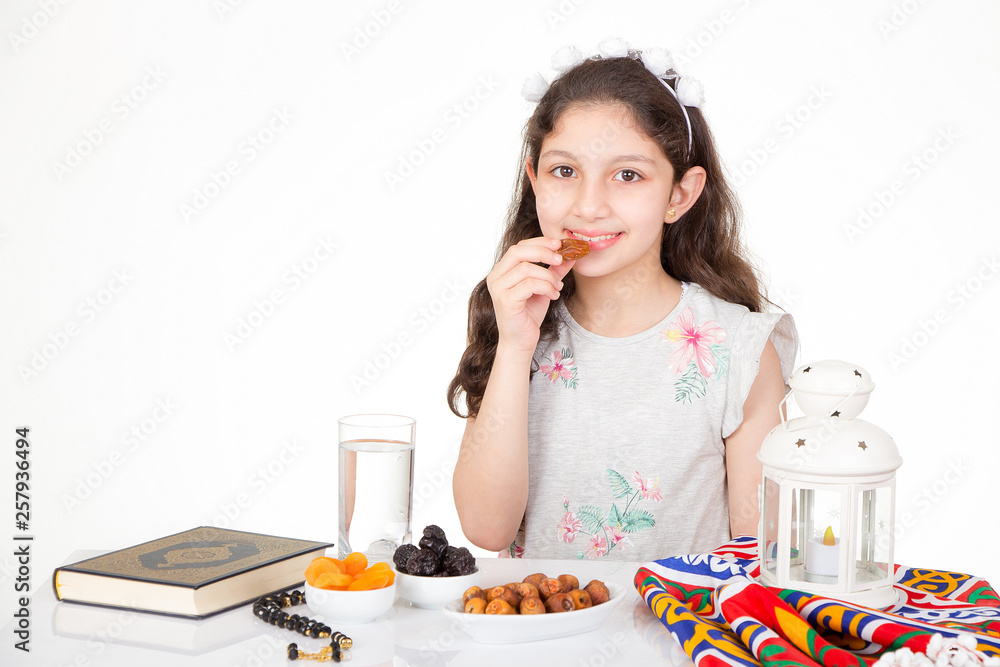 Happy young Muslim girl eating dates for iftar - breakfast in holy Ramadan Happy young Muslim girl eating dates for iftar - breakfast in holy Ramadan