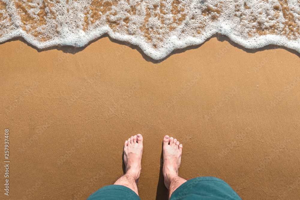 Feet stand on sea sand and wave with copy space, Vacation on ocean beach, Summer holiday.