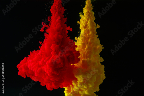 A cloud of colored acrylic paint in water. A drop of colorful ink dissolves in water on a black background. Abstract background.