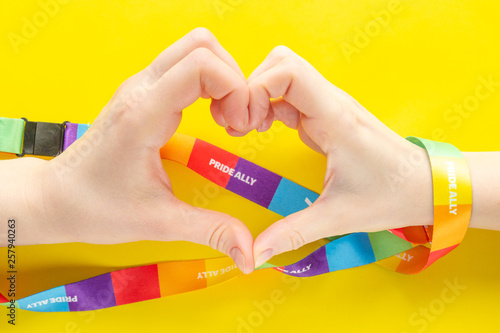 LGBT concept - two hands wrapped with a rainbow ribbon stacked together in a sign of the heart, inside of which the inscription pride ally