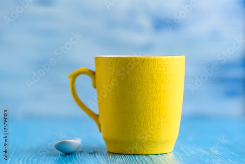Yellow mug on a wooden background photographed close-up.