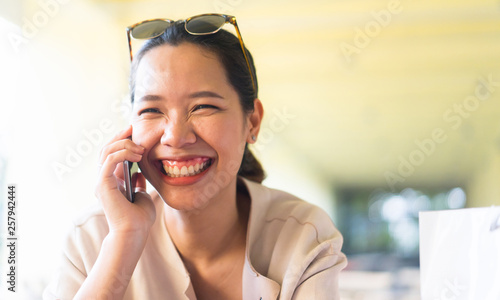 close up young pretty asian woman smiling while talking by smartphone in freedom time , lifestyle person concept photo