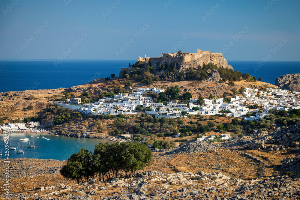 View of Lindos Acropolis with city against blue sky View of Lindos Acropolis with city against blue sky