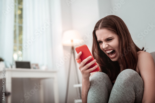 Stressed girl shouting at her smartphone while texting