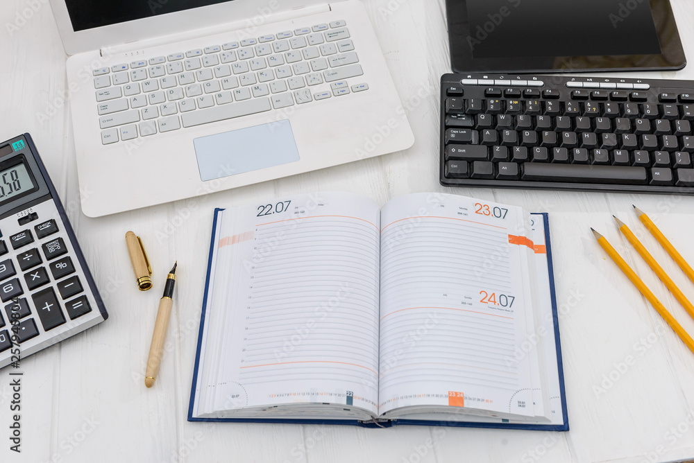 Diary with laptop on desk, workplace concept Diary with laptop on desk, workplace concept