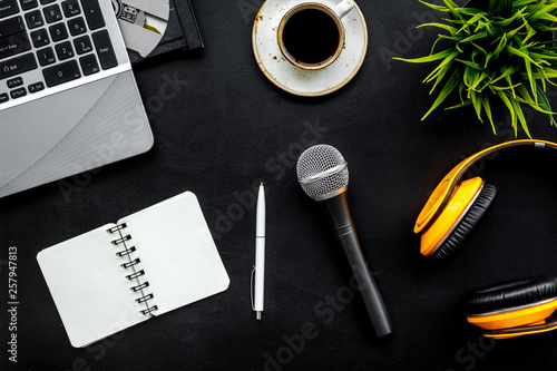 blogger, journalist or musician work space with microphone, notebook, laptop and headphones on black background top view mock up