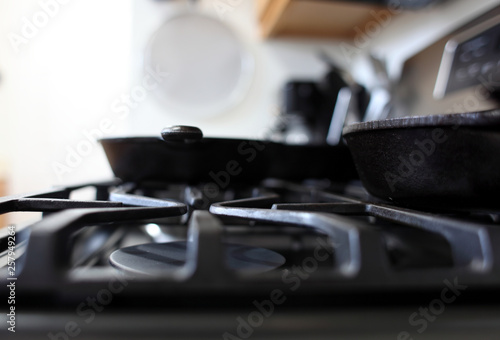 Modern stainless steel gas stove with cast iron skillets in a home kitchen.