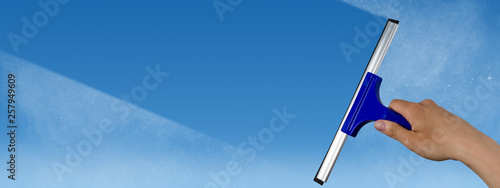 squeegee cleaning a dirty window, spring cleaning concept, blue sky with copy space