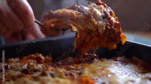 serving hot dishes. cook puts a portion of lasagna on a plate