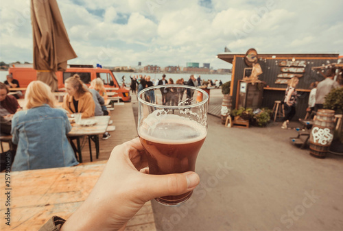 Foto Craft beer glass in drinker hand on street food market of Copenhagen, Denmark