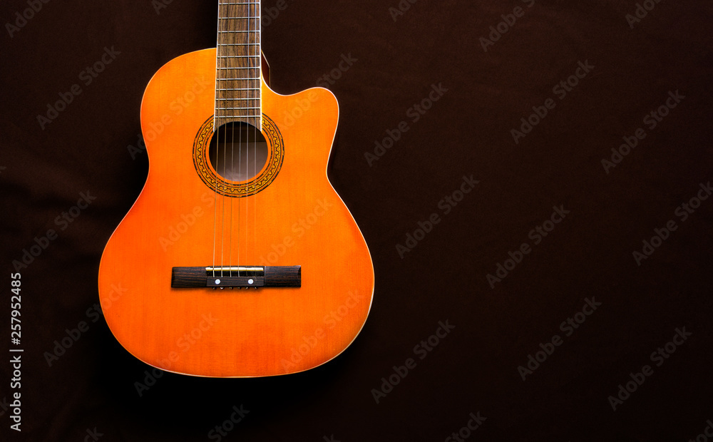 Six-string acoustic guitar on a dark brown background. Classical Spanish guitar. Musical instrument. Place for text.
