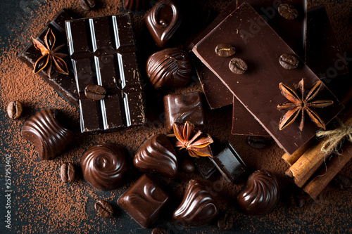 Assortment of dark, white and milk chocolate stack, chips. Chocolate and coffee beans on rustic wooden sacking background. Spices, cinnamon. Selective macro focus. Chocolates background. Sweets