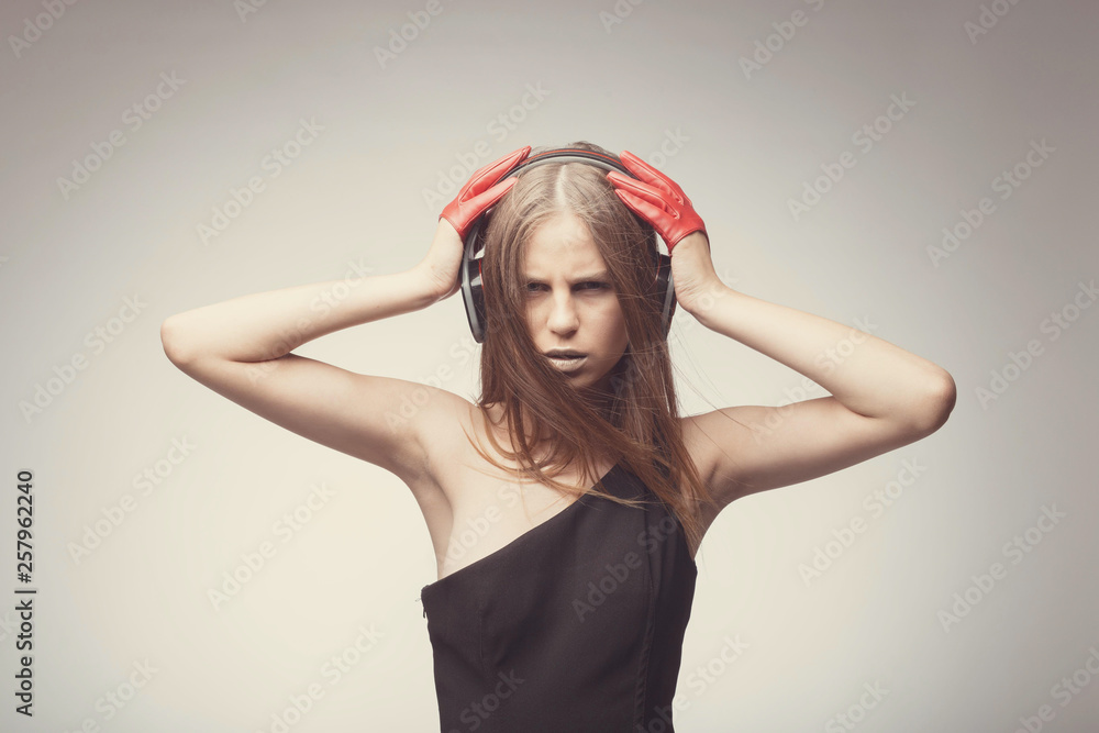 Fototapeta premium Fashion pretty girl listening music with headphones, wearing red gloves, and disappointed with bad music. Lifestyle woman concept