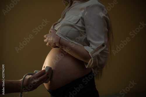 female doctor operating ultrasound scanner examining belly of her female patient