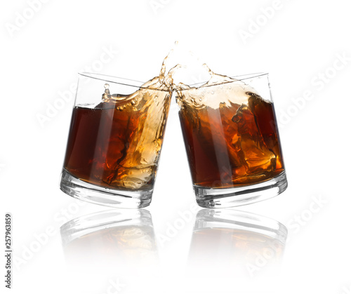 Glasses of expensive whiskey clinking together and splashing on white background