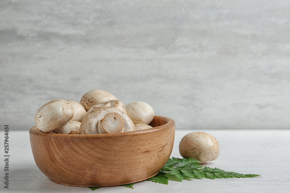Bowl with fresh champignon mushrooms on wooden table, space for text Bowl with fresh champignon mushrooms on wooden table, space for text