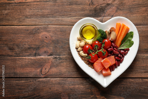 Plate with heart-healthy diet products on wooden background, top view. Space for text