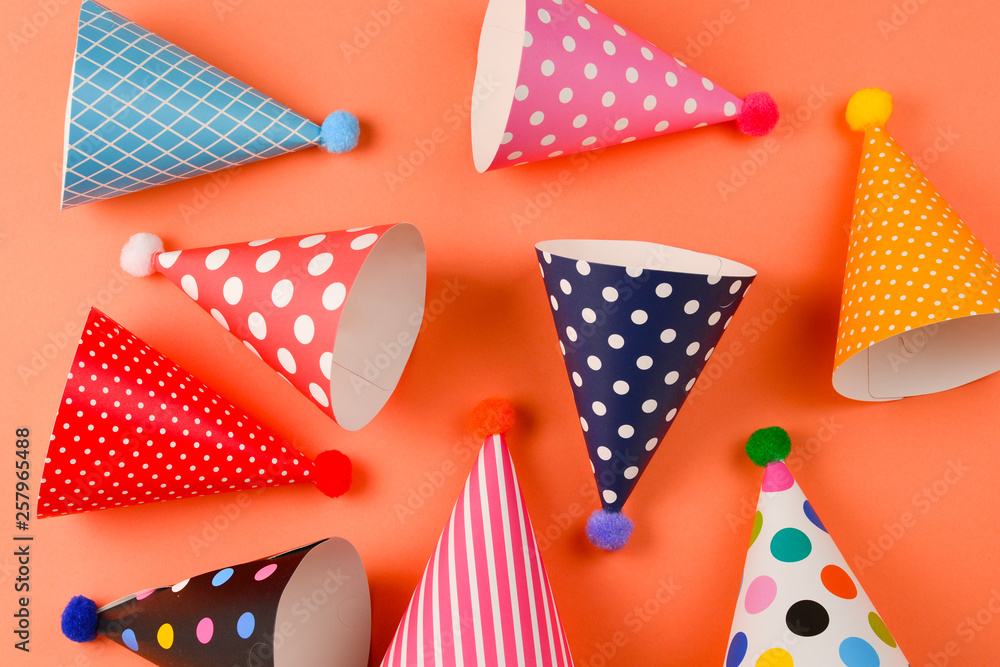Obraz premium Colorful birthday caps on orange background. Top view.