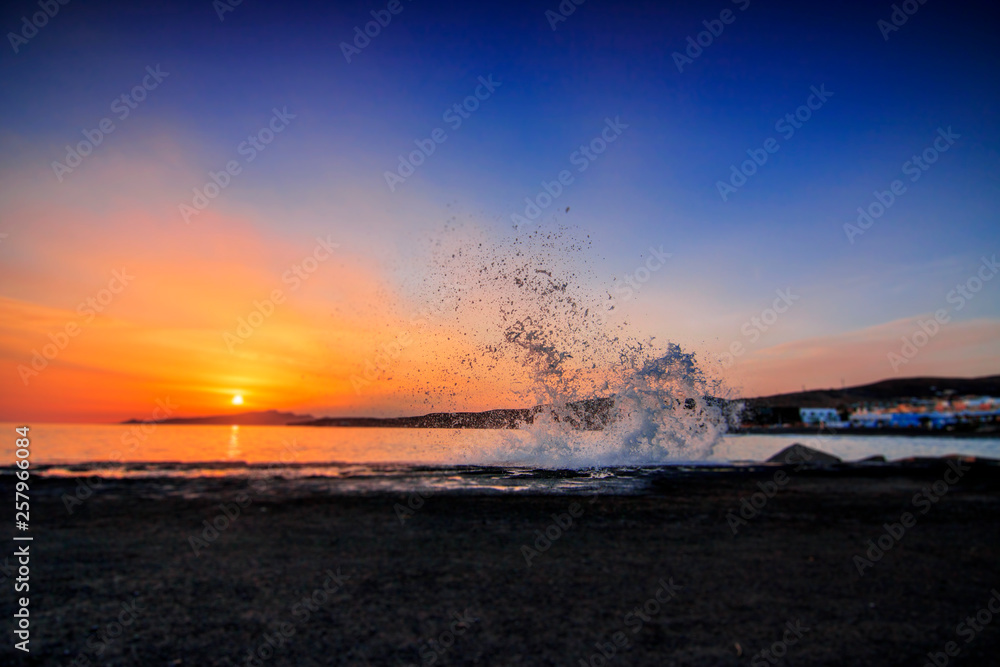 Sunset on a coast of Fuerteventura Canarias in Spain. splashing wave, black lava sand and great evening red