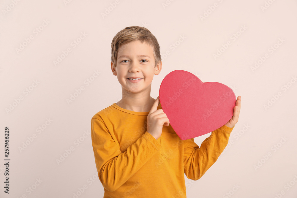 Cute boy holding heart shaped box on white background Cute boy holding heart shaped box on white background
