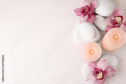 Flat lay composition with zen stones, candles and flowers on wooden background. Space for text