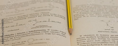 żółty ołówek na tle książki do chemii