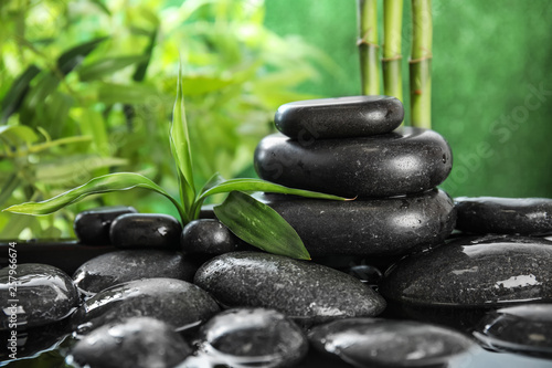 Zen stones and bamboo leaves in water on blurred background. Space for text