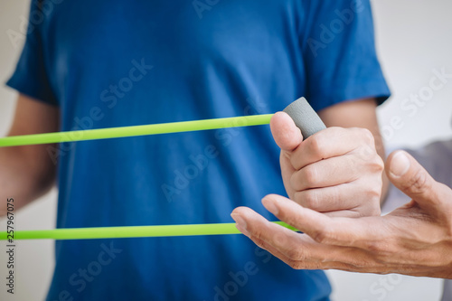 Doctor physiotherapist assisting a male patient while giving exercising treatment on stretching his arm with exercise band in the clinic  Rehabilitation physiotherapy concept