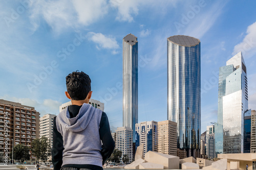 Young kid looking at Abu Dhabi city - Architecture and famous skyscrapers of Abu Dhabi skyline with beautiful clouds, World Trade Center, UAE photo