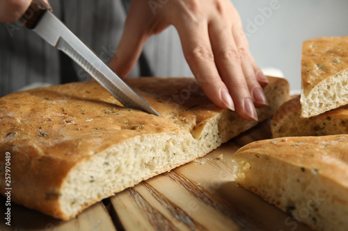 Woman cutting bread on wooden board, closeup