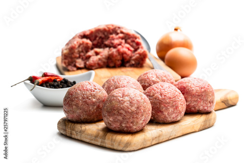 Raw meat balls on wooden cutting board isolated on white