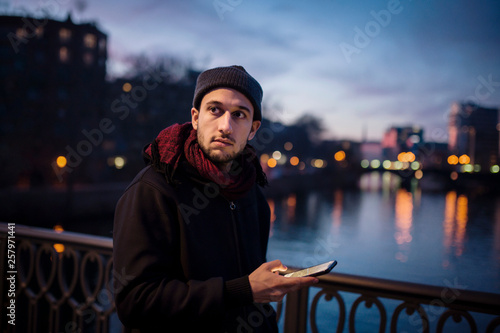 Tableau sur toile Junger Mann mit Smartphone im Abendlicht