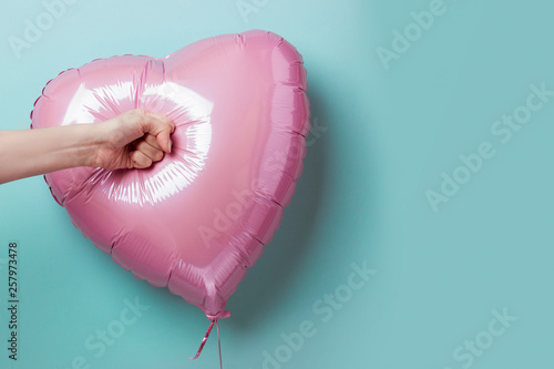 Bild auf Leinwand Female hand punching a heart-shaped balloon