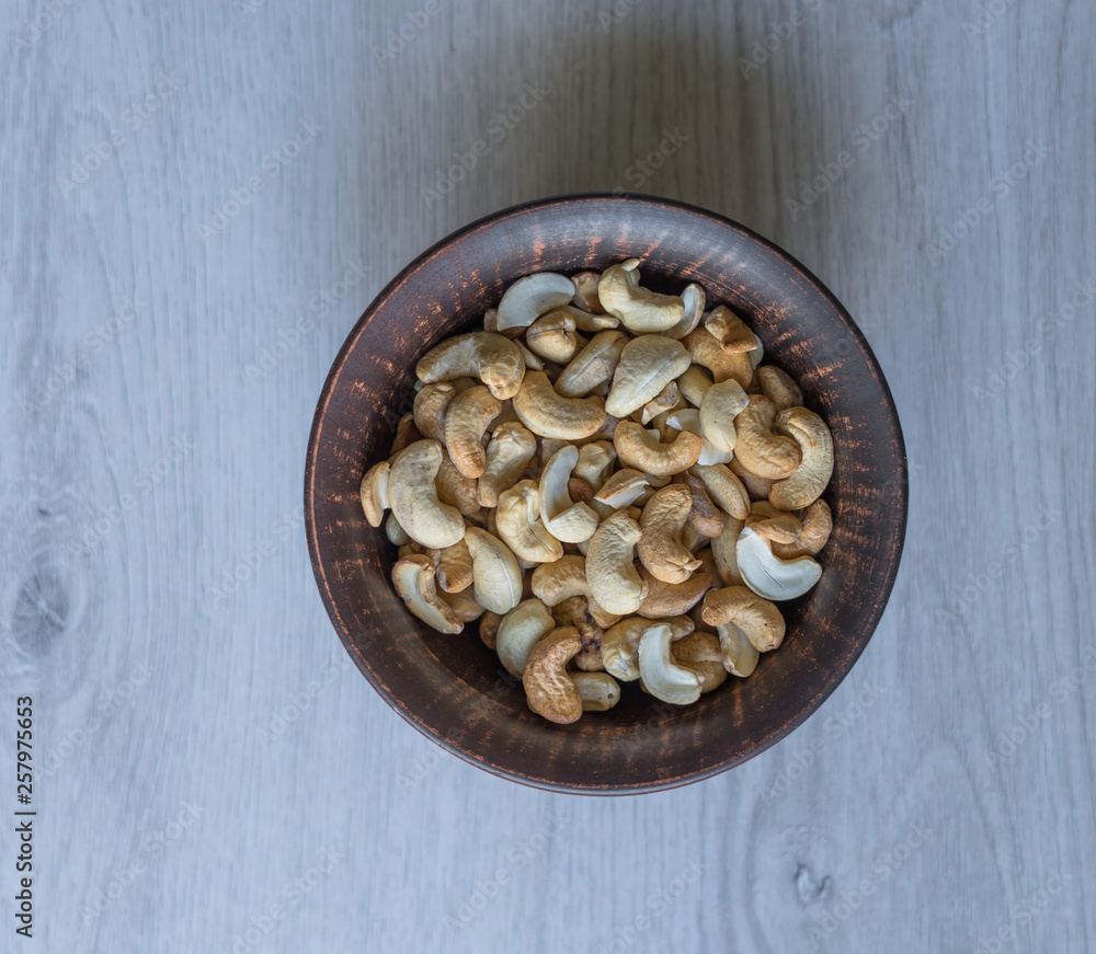 Healthy food for background image close up cashew nuts. Nuts texture on white grey table top view on the cup plate Healthy food for background image close up cashew nuts. Nuts texture on white grey table top view on the cup plate