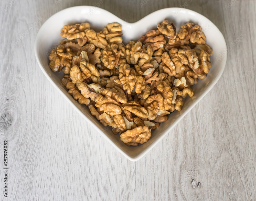 Nuts arranged in heart on background. Healthy Food image close up walnuts nuts. Love Texture on white grey table top view background on the cup plate Nuts arranged in heart on background. Healthy Food image close up walnuts nuts. Love Texture on white grey table top view background on the cup plate