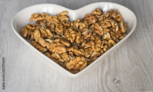 Nuts arranged in heart  on background. Healthy Food image close up walnuts nuts. Love Texture on white grey table top view background on the cup plate